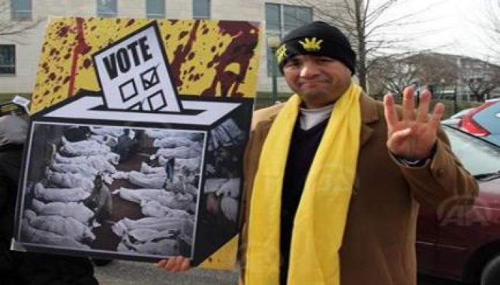 متظاهر مصري في واشنطن يحمل صندوق الاستفتاء بداخلة نماذج لجثث شهداء الانقلاب