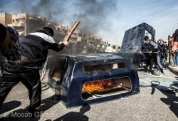 ثوار أكتوبر يحطمون ويشعلون النار في سيارة شرطة حاولت الاعتداء عليهم (صور)