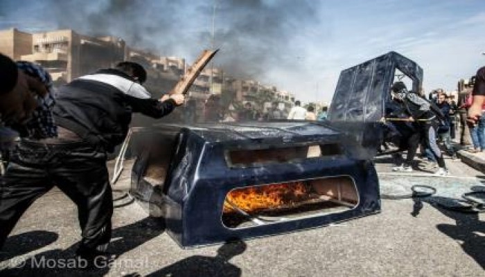 ثوار أكتوبر يحطمون ويشعلون النار في سيارة شرطة حاولت الاعتداء عليهم (صور)