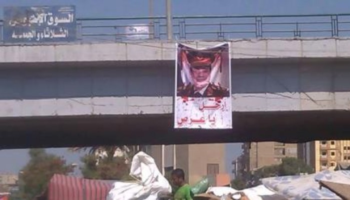 بالصور :  شباب يعلقون بنر بهاشتاج السيسي أعلي الكوبري العلوي بوسط الفيوم