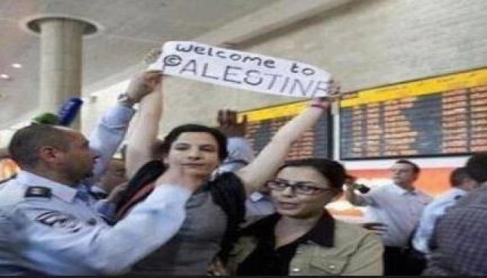 بالصور : فتاة أمريكية ترفع لافته مرحباً بكم في فلسطين فور هبوطها بمطار تل أبيب