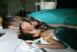 بالصور:الطبيب النرويجي د. مادس جيلبرت يقبل رأس طفل شهيد في غزة..فأين العرب !